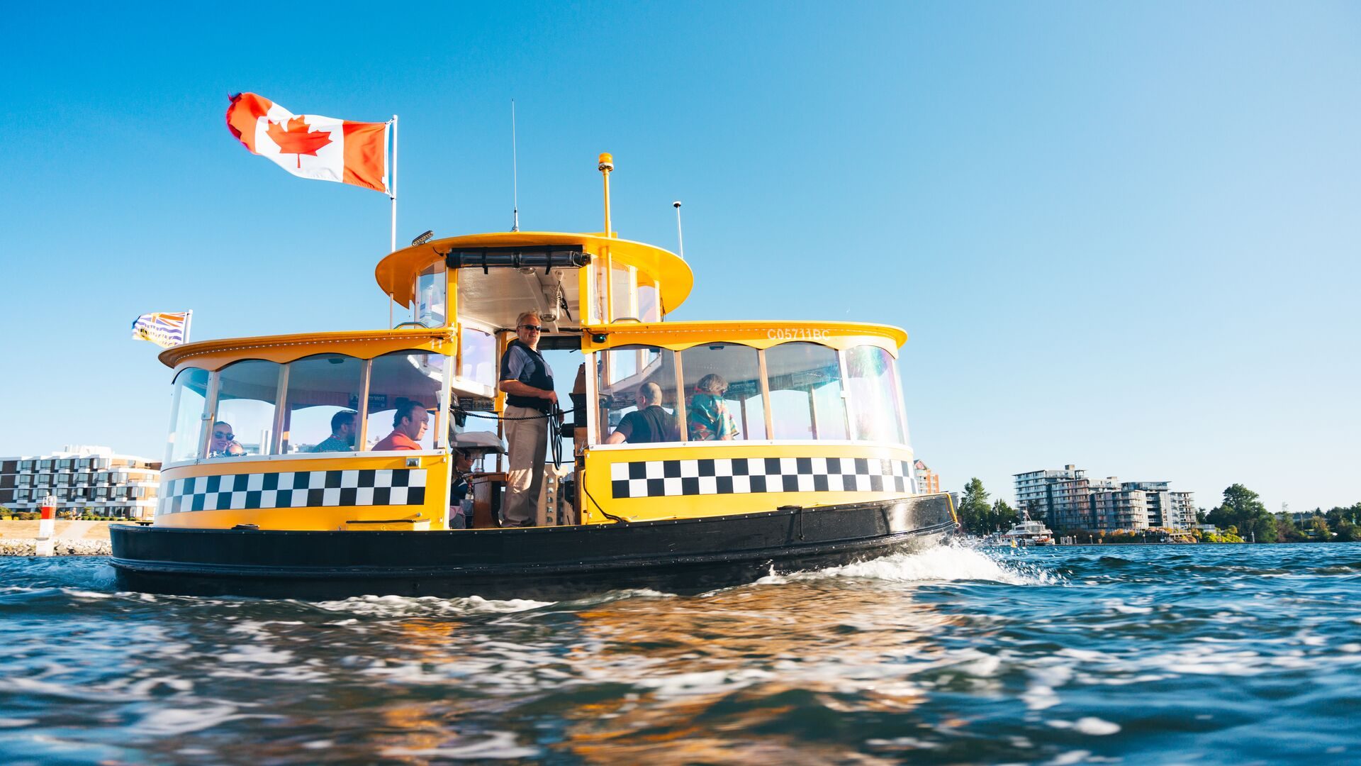 A yellow harbour ferry flying a Canadian flag on Victoria's Inner Harbour
