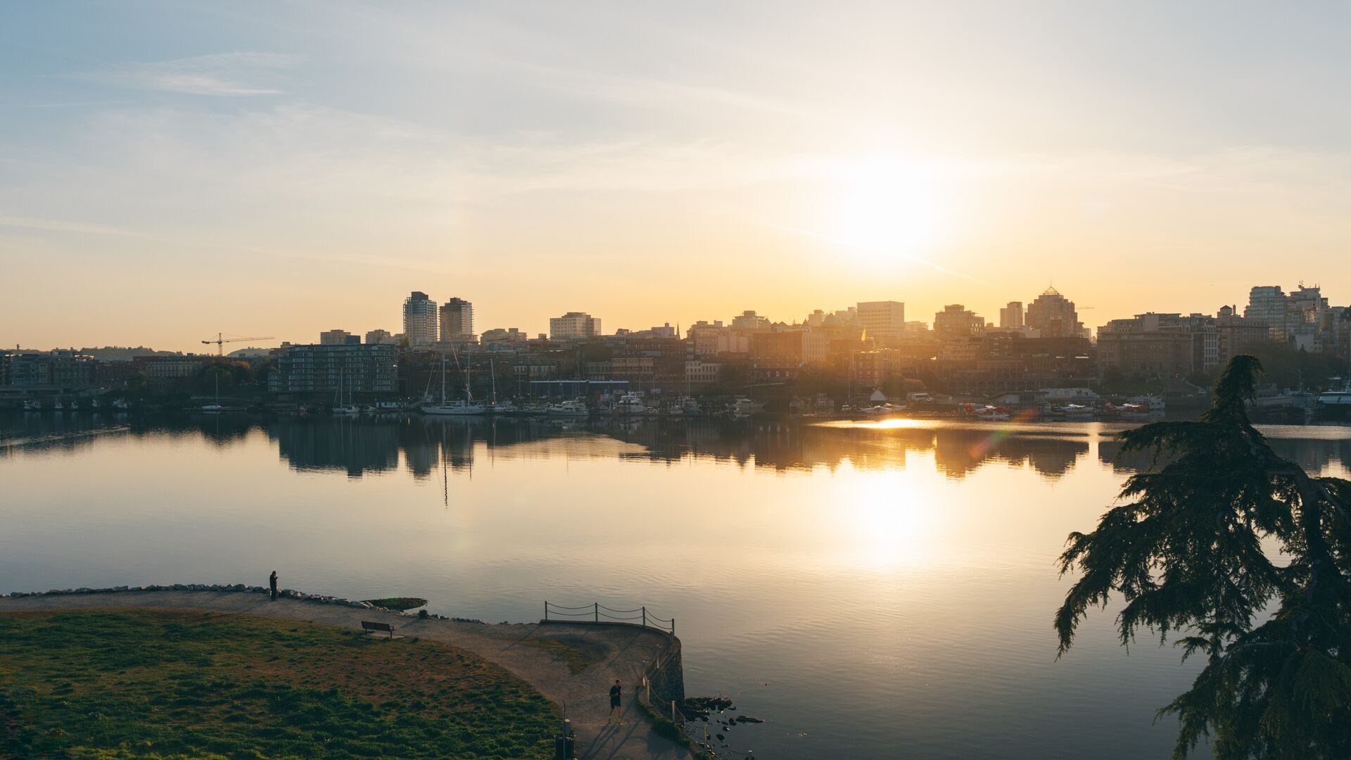 The sun setting over still water with the city skyline beyond