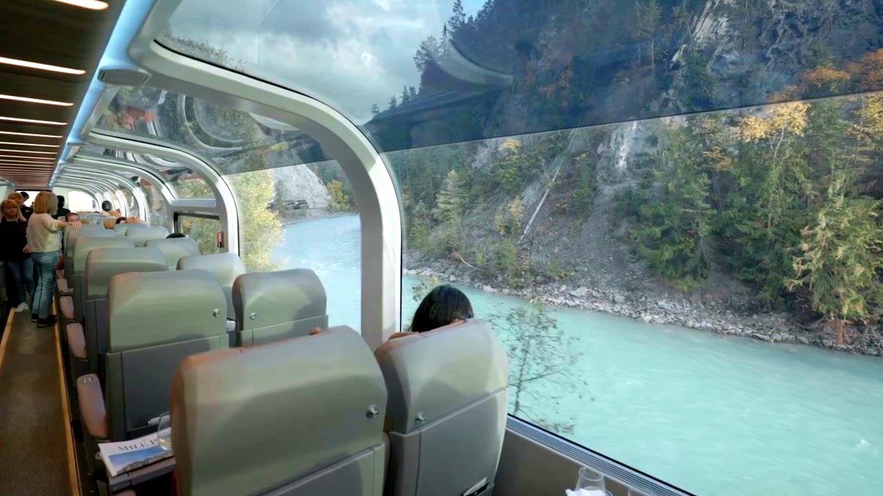 Passengers in a Rocky Mountaineer glass-domed coach looking out at the river valley
