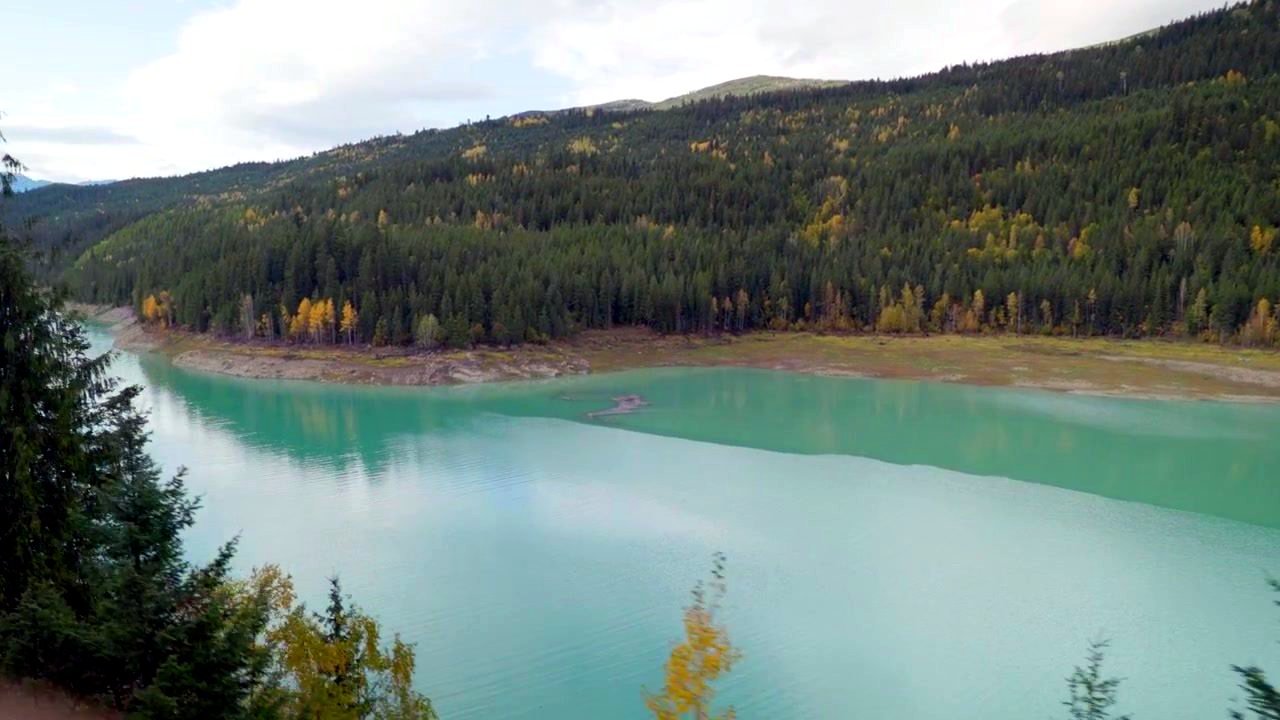 A turquoise lake below forested hills