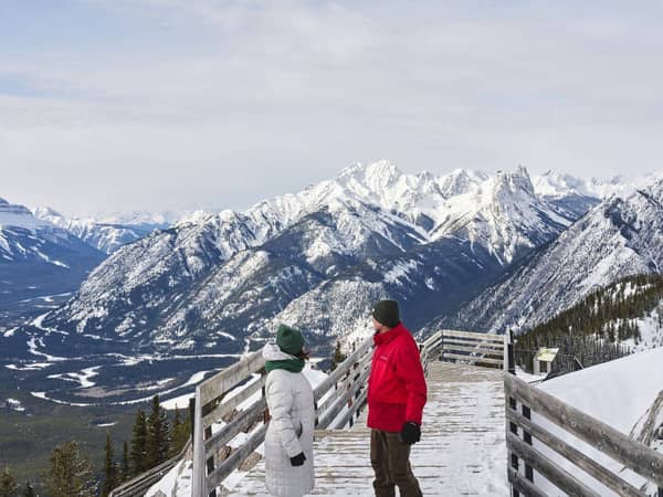Two visitors on a viewing platform above the snowy peaks of the Bow Valley
