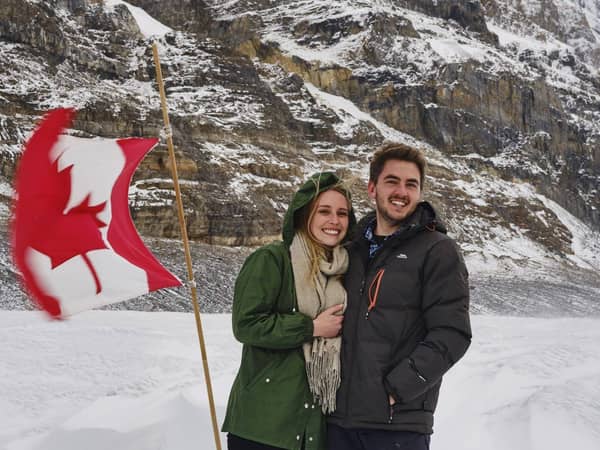 A couple smiling on the Columbia Icefield beside a Canadian flag