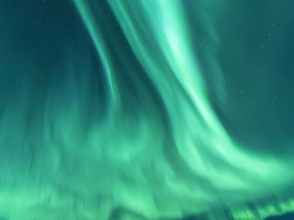 Ribbons of green and teal northern lights filling the sky