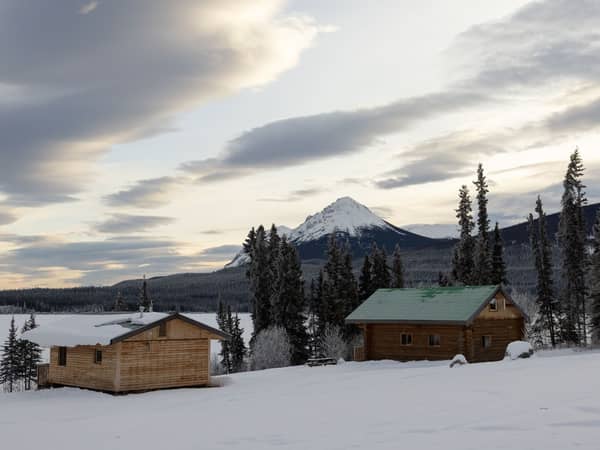 Wooden cabins beside a frozen lake beneath a soft winter sky