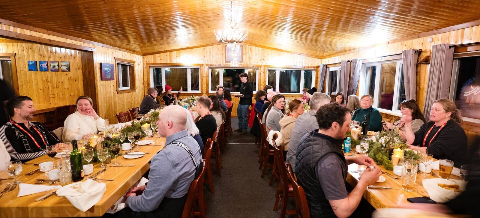 A long dining table of guests inside a timber lodge