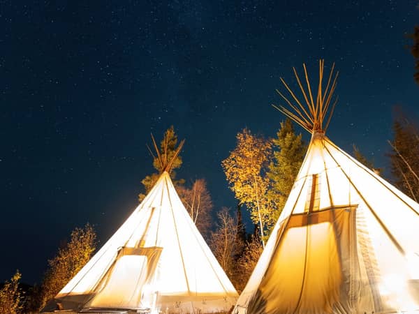 Two glowing tipis against the night sky