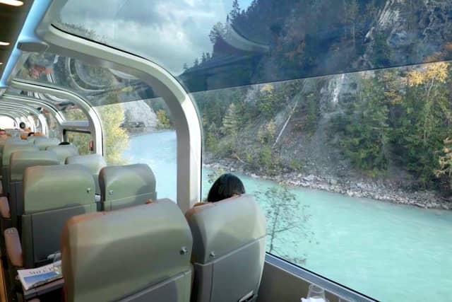 Passengers in a Rocky Mountaineer glass-domed coach looking out at the river valley