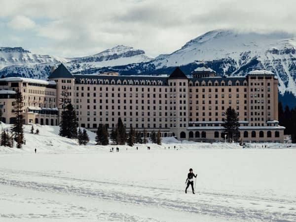 Fairmont Chateau Lake Louise above a snowy frozen lake with a skier in front