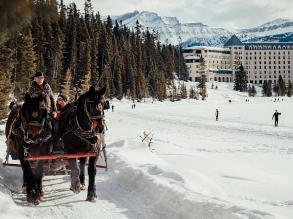 A horse-drawn sleigh crossing the snow in front of Fairmont Chateau Lake Louise